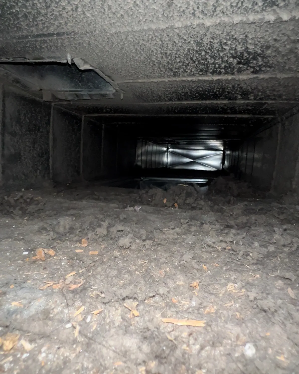 Second trunk-line interior with debris on duct floor before cleaning